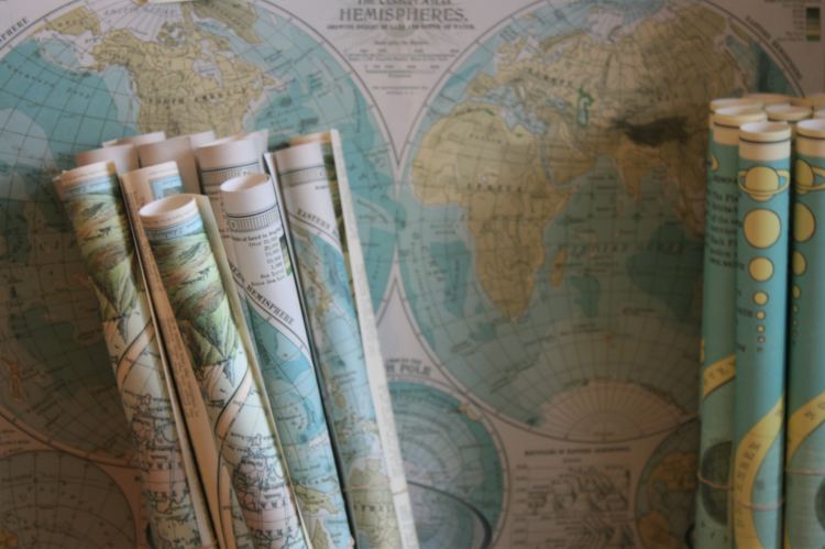 photo of several rolled maps held vertically in a basket against a background of a world map
