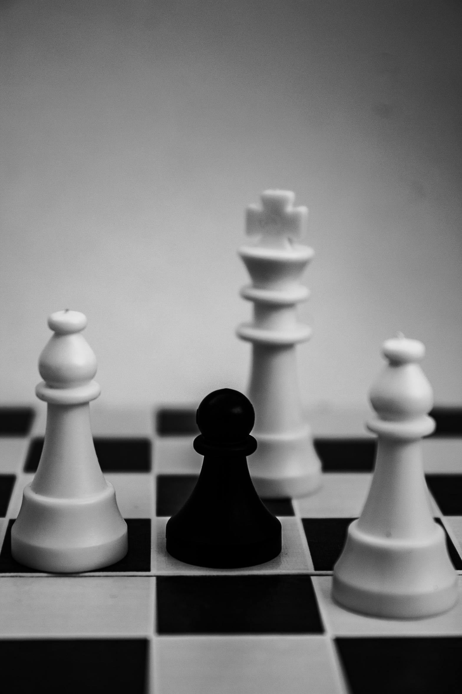 White chess pieces surrounding single black pawn piece