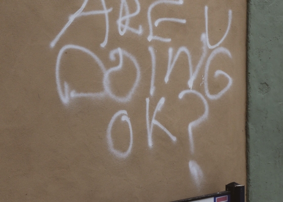 Beige outdoor wall spray painted "are u doing OK?"
